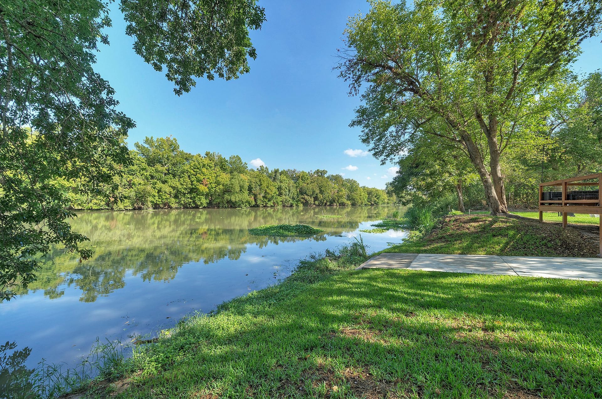 Grassy bank of the Colorado River behind River Bend Bliss in Cedar Creek, TX