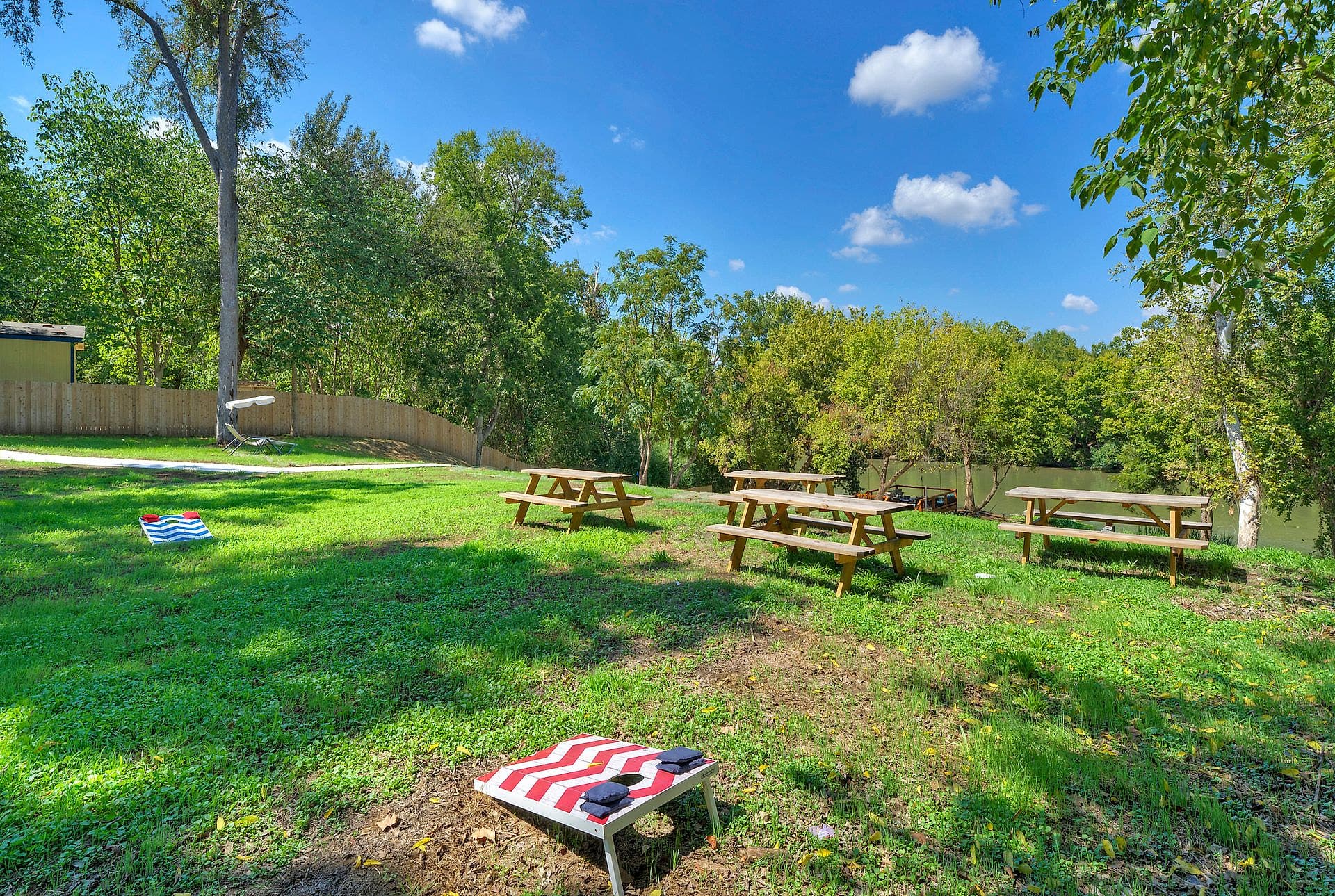 Picnic tables and cornhole boards on the shared lawn at River Bend Bliss